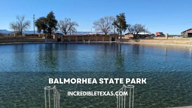 Crystal clear spring waters of San Solomon Springs pool with diving board and desert mountain foothills in Balmorhea