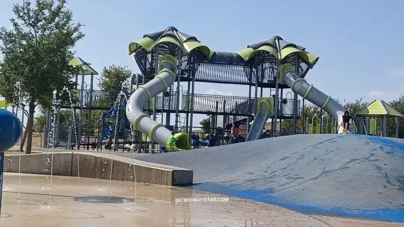 Expansive green hills, playgrounds, and splash pad pavilions at Pearsall Park in San Antonio