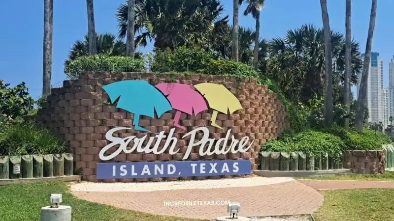 Emerald Gulf waters and white sandy shoreline at South Padre Island Texas with beachgoers under umbrellas