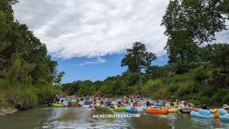 Clear emerald waters and tubers floating the San Marcos River under lush cypress trees