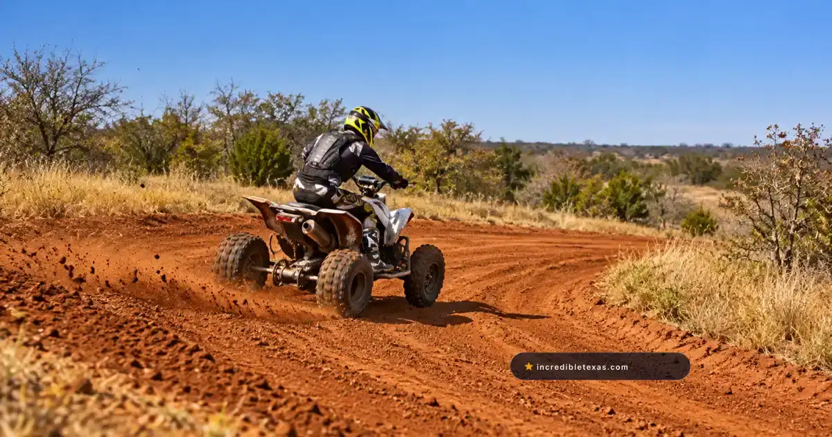 Helmeted ATV rider follows a red dirt trail through North Texas scrub near Dallas