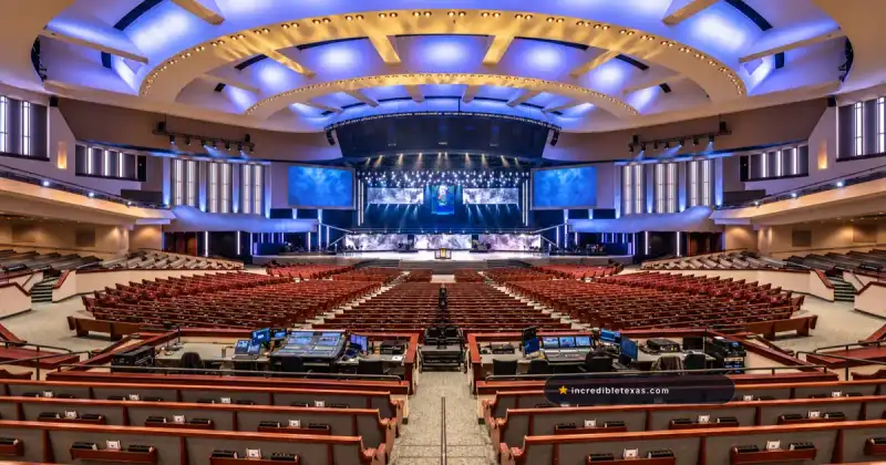 Prestonwood Baptist Church auditorium in Plano, with curved pews, a broad stage, and an illuminated vaulted ceiling