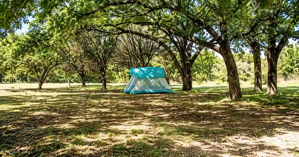 Turquoise tent beneath mature shade trees at Cleburne State Park