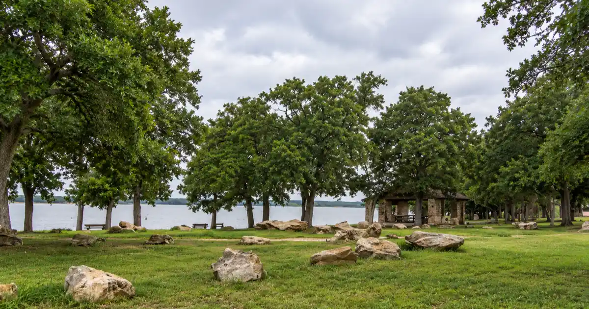 Oak-shaded lakeshore picnic area with limestone boulders at Fort Parker State Park