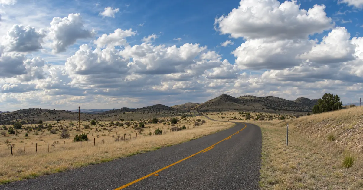 Two-lane pavement crosses open grassland beneath the Davis Mountains on the scenic loop.