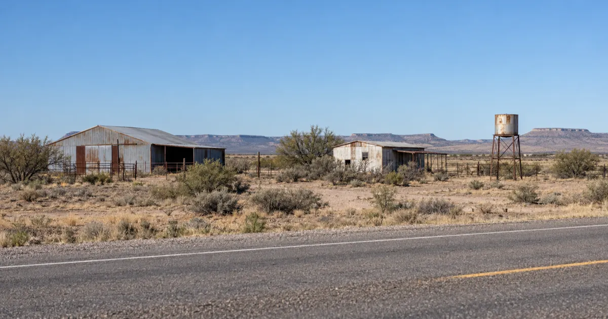 Weathered outbuildings beside US 90 in the dry desert landscape at Lobo, Texas